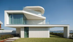 A modern house with white walls and large glass windows overlooking a body of water.