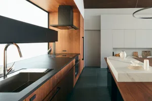 A modern kitchen featuring wood cabinets and a marble countertop.