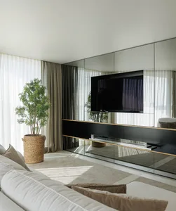Modern living room featuring metallic black acrylic shelving and furniture, white sofas, and large windows with sheer curtain