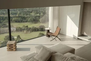 Modern living room featuring minimalist furniture and soft textiles with a view of greenery outside.