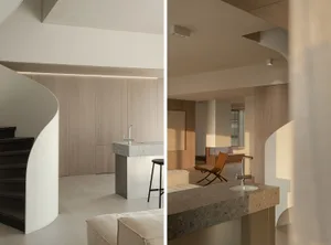 現代簡約住宅室內，採用木質牆面、石材檯面，以及流線型曲線樓梯。