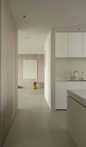 Modern minimalist kitchen with concrete flooring, white cabinets, and a minimalist light fixture.