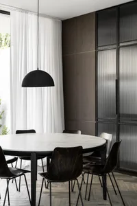 Modern minimalist dining room with marble table and dark wooden chairs