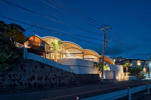 A modern residential house with curved concrete facade at night.