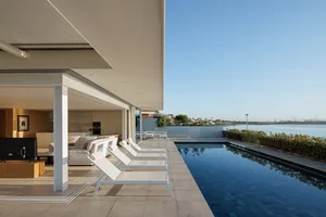 Modern residential exterior with glass walls and concrete patio.