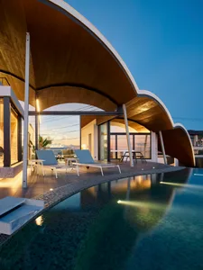 A modern residential exterior featuring glass, steel, and stone materials.