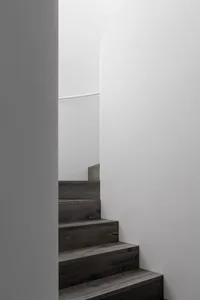Modern wooden staircase inside a white, minimalist interior.