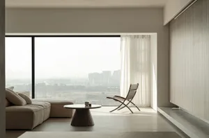 A modern living room with minimalist design, featuring neutral-toned furniture, and a large window offering a view of a citys