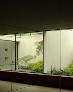 A minimalist modern interior with concrete walls and floor, natural lighting, and greenery.