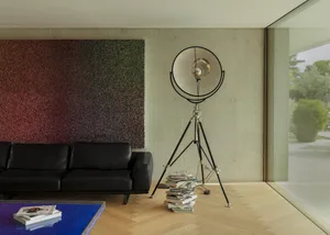 Modern living room featuring a concrete wall, a black leather sofa, and a large tripod floor lamp.