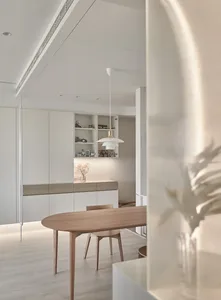 A modern minimalist dining room featuring a wooden table, glass shelves, and metal accents.