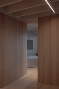 A minimalist bedroom featuring wood paneling and soft lighting.