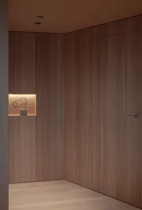 A minimalist closet with wooden panels and a small shelf with a sculptural object.