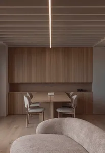 A minimalist residential dining room featuring wooden furniture and a sleek table with chairs.