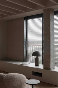 A modern minimalist living room with concrete walls, wooden floor, and white furniture.