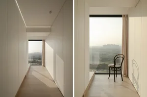 A minimalist interior with hardwood flooring and large windows overlooking a cityscape.