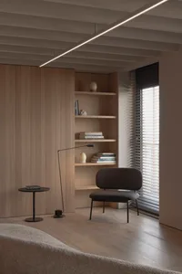A modern living room featuring a wooden wall, shelves, and a chair.