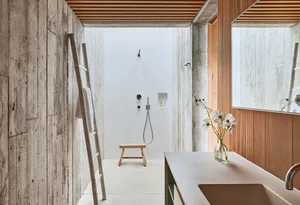 A modern bathroom with concrete walls, wooden accents, and a simple, minimalist design.