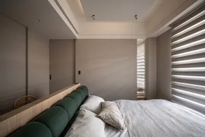 A modern minimalist bedroom featuring a textured fabric headboard and wooden furniture, with a glass door and soft lighting.