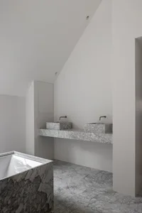 Modern minimalist bathroom with marble accents, featuring a vessel sink and a freestanding bathtub.