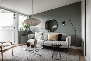 A modern minimalist living room with a grey couch, wooden floor, and metal coffee table.