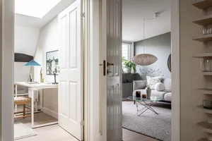 A contemporary, minimalist living room featuring soft, neutral-toned materials and a modern, hanging lamp.