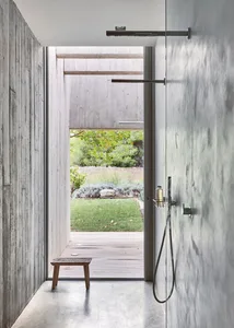 Modern bathroom with concrete walls and floor, featuring a walk-in shower with a view of the outdoor patio