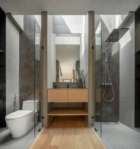 Modern bathroom with concrete walls and floors, featuring a sleek sink, toilet, and shower with wooden accents.