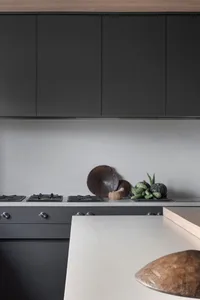 Modern kitchen with black cabinets and a natural stone countertop.