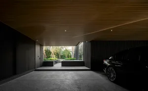 Modern carport with dark metal walls and a black car parked inside.