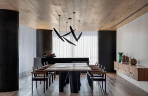 A modern dining room with a wooden table and chairs, featuring a unique pendant light fixture and a sleek, contemporary desig