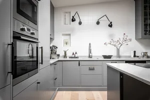 Modern minimalist kitchen with gray cabinets, white countertops, and white backsplash tiles.