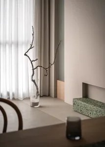 Modern minimalist interior design featuring glass vase with branches on a window sill.