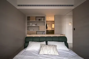 A modern minimalist bedroom featuring neutral materials and a white bed with a green upholstered headboard.