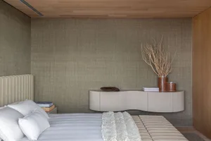 Minimalist bedroom featuring textured wallpaper and wooden furniture.