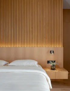 A modern minimalist bedroom featuring a wooden texture headboard and bed frame, with a white duvet and pillows.
