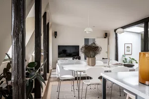 Minimalist living and dining room with modern furniture, white walls, and black wood accents.