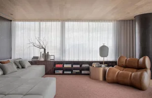 A modern minimalist living room with a large window, grey sofa, brown armchairs, and a coffee table.
