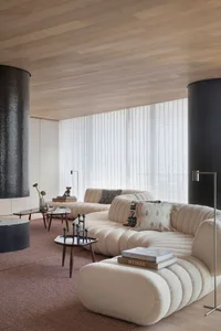 Modern minimalist living room featuring a textured fabric sofa, geometric patterned pillows, and sleek coffee tables.
