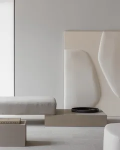 A minimalist living room with white-painted walls and concrete furniture.