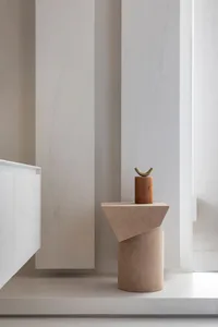 A minimalist side table with a terrazzo finish, featuring a single flowerpot on top.