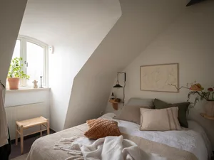A minimalist bedroom with a bed, pillows, and a blanket.