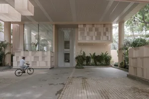 A modern, concrete-based architectural interior design featuring an open-plan space with large windows and plants.