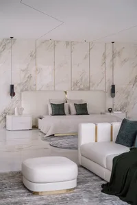 A modern bedroom featuring marble accents, a minimalist design, and a plush seating area.