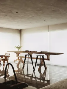 A minimalist living room with a concrete table and stools.