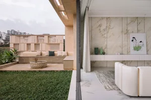A minimalist living room featuring marble flooring and walls, with a white sofa and green plants on a small patio.