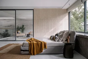 A modern bedroom featuring gray cushions and a yellow throw blanket on a gray sofa, with a view of green foliage outside.