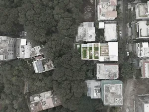Aerial view of modern housing development with concrete roofs and surrounding greenery.
