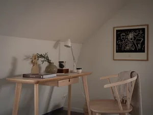 A simple, modern home office features wooden furniture and minimalist design elements, with a focus on functionality and styl