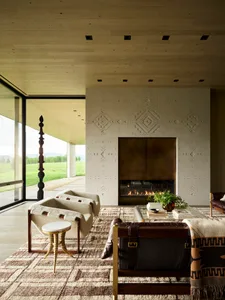 A modern industrial living room with a fireplace, leather chairs, and concrete walls.